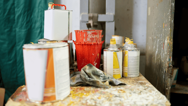 Paint tins, paint thinners, and rags on a table.